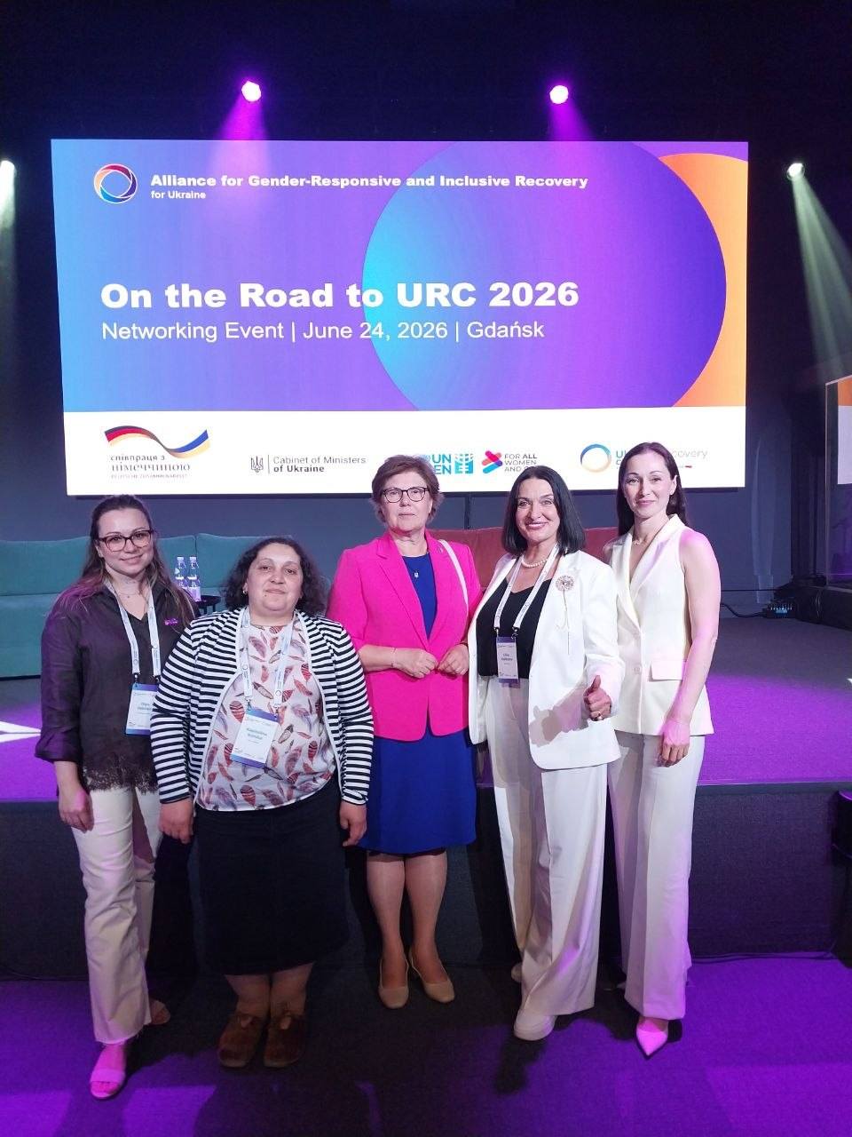 Учасниці нетворкінг-заходу «On the Road to URC 2026» біля екрана з програмою події в Гданську